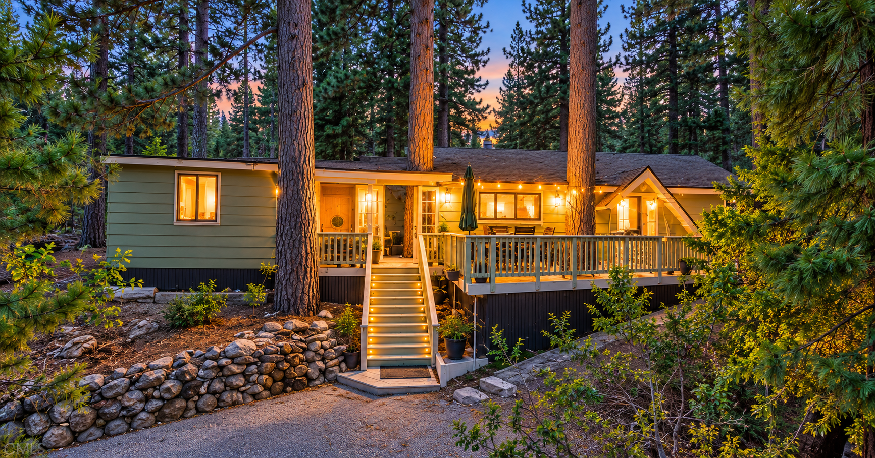 Snow-covered mountain home in Big Bear Lake, California with elevated wood decks and pine trees
